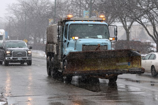 A snow plow travels east on West 47th Street near Hoyne Avenue in Chicago as snow falls on Dec. 22, 2022.