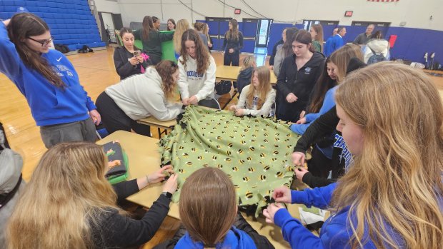 Members of various athletic teams at Aurora University work on a blanket Tuesday as part of an effort to support Project Linus, which gives blankets to children in hospitals, shelters, group homes and more.