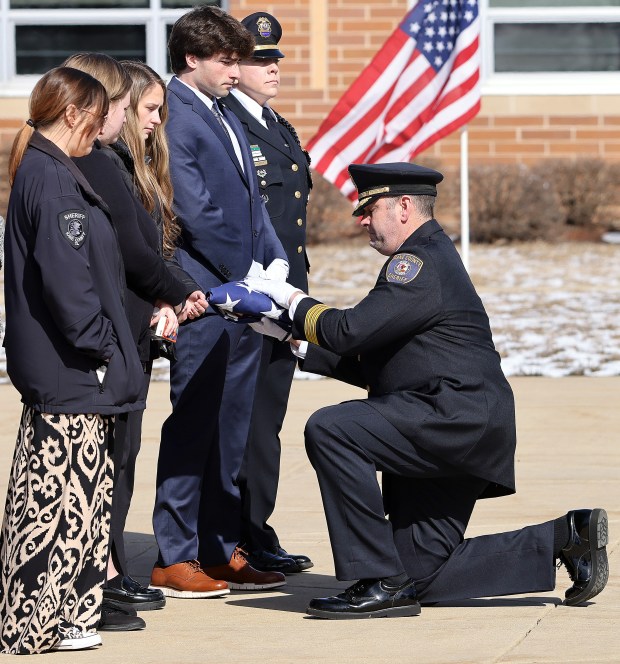 Kane County Sheriff Ron Hain presents a flag to the family of Deputy Christopher Ruchaj, on Saturday, Feb. 23, 2024 at Kaneland Harter Middle School in Sugar Grove. Ruchaj died suddenly of a heart attack on Feb. 14.Ruchaj was the Community Resource Officer at Kaneland High School in Maple Park and a well-known figure in the Kaneland community. H. Rick Bamman / For the Beacon-News