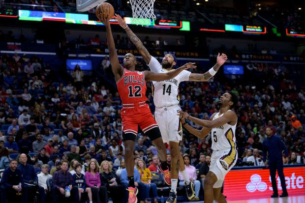 Chicago Bulls guard Ayo Dosunmu (12) shoots against New Orleans Pelicans forward Brandon Ingram (14) during the first half of an NBA basketball game in New Orleans, Sunday, Feb. 25, 2024. (AP Photo/Matthew Hinton)