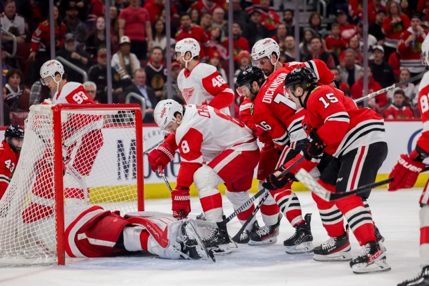 Chicago Blackhawks right wing Joey Anderson (15) and Chicago Blackhawks center Jason Dickinson (16) fight Detroit Red Wings defenseman Ben Chiarot (8) for possession of the puck after Detroit Red Wings goaltender James Reimer (47) fell in the net during the first period at the United Center Sunday Feb. 25, 2024 in Chicago. (Armando L. Sanchez/Chicago Tribune)