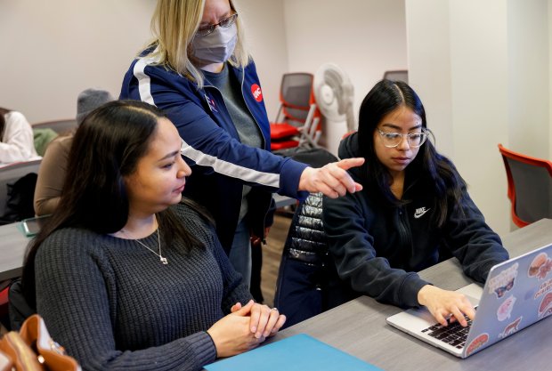 Ashton Spatz, center, a financial aid adviser with the University of Illinois at Chicago, assists Jessena Sanchez, left, and her daughter, Leslie Delve, a sophomore at UIC, during a FAFSA workshop on Feb. 23, 2024, at the Student Financial Aid Office. (Vincent Alban/Chicago Tribune)