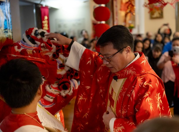 Father Frances Li blesses the lion as St. Therese Chinese Catholic Church celebrates Lunar New Year during Mass on Feb. 11, 2024. (Brian Cassella/Chicago Tribune)