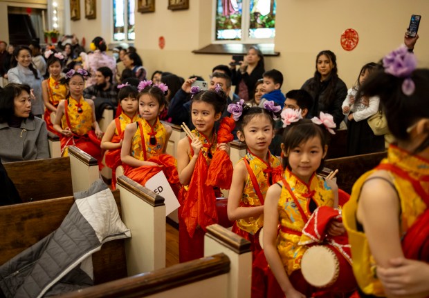 Performers from St. Therese School watch as a lion dance is performed down the aisles to celebrate Lunar New Year during Mass on Feb. 11, 2024, at St. Therese Chinese Catholic Church in Chinatown. (Brian Cassella/Chicago Tribune)