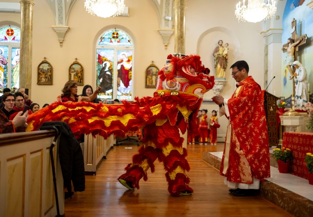 Father Frances Li offers a red envelope gift during a lion dance to celebrate Lunar New Year during Mass on Feb. 11, 2024, at St. Therese Chinese Catholic Church in Chinatown. (Brian Cassella/Chicago Tribune)