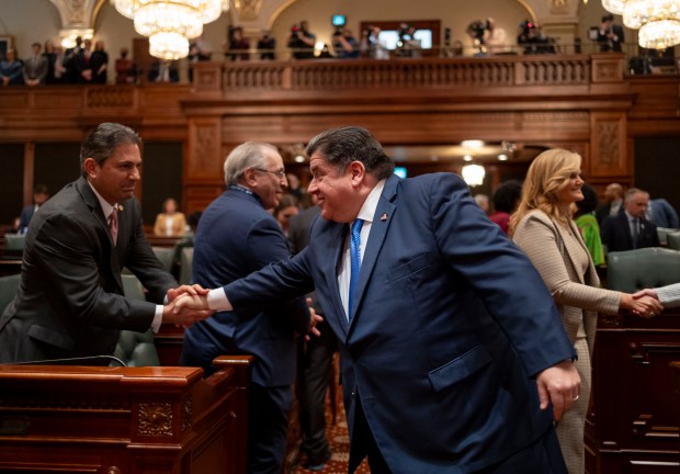 Gov. J.B. Pritzker greets state Rep. Anthony DeLuca as he arrives to deliver his State of the State and budget address before the General Assembly at the Illinois Capitol building on Feb. 21, 2024. (Brian Cassella/Chicago Tribune)