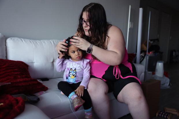 Kimberly Riquelme fixes her daughterJasmine's hair at their new apartment on Chicago's North Side on Feb. 19, 2024. They were homeless for 10 months. (Chris Sweda/Chicago Tribune)