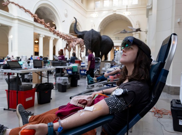 Samantha Peterson wears a mixed reality headset to see an augmented view of the Field Museum while giving blood, Feb.. 27, 2024. Abbott created the headsets to provide a distraction and relieve stress during blood donations. (Brian Cassella/Chicago Tribune)