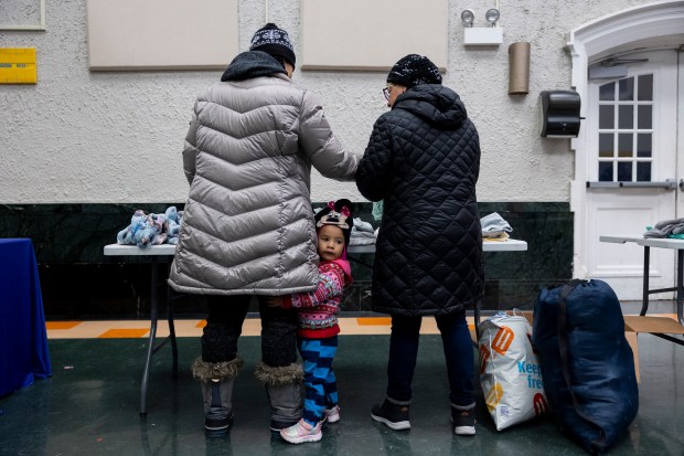 Frida Peña, 2, center, holds onto the leg of her mother, Daniella Narvaez, while looking for clothing and other supplies on Saturday, Feb. 24, 2024, at a supply drive called "Freebies for Families" hosted by Southwest Collective at Edwards Elementary in Chicago. The collective gave out diapers, baby formula, clothing, shoes, and other supplies. (Vincent Alban/Chicago Tribune)