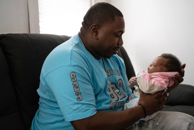 Jermaine Harris holds his newborn daughter AJ on Dec. 26, 2023. Harris' father, Lee Harris, died eight months after getting out of prison and just before the birth of his granddaughter. Harris had served 33 years in prison and was ultimately exonerated. (E. Jason Wambsgans/Chicago Tribune)