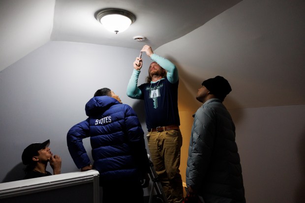 Daniel Antonio Ruiz, 21, from left, Abel Gonzalez, 27, property manager Chris Amatore and Robinson Covis, 25, gather upstairs while Amatore installs a smoke detector inside a home shared by several Venezuelan migrant families in the Roseland neighborhood of Chicago on Jan. 29, 2024. (Armando L. Sanchez/Chicago Tribune)