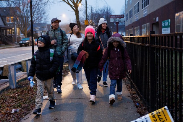 Jeremy Hernandez, 10, from left, Francisco Hernandez, 31, Joselin Mendoza, 29, Yesmary Mendoza, 9, Maria Malpica, 28, and Ireanyerlin Hernandez, 8, walk to a bus stop while commuting to school in Roseland on Jan. 30, 2024. (Armando L. Sanchez/Chicago Tribune)