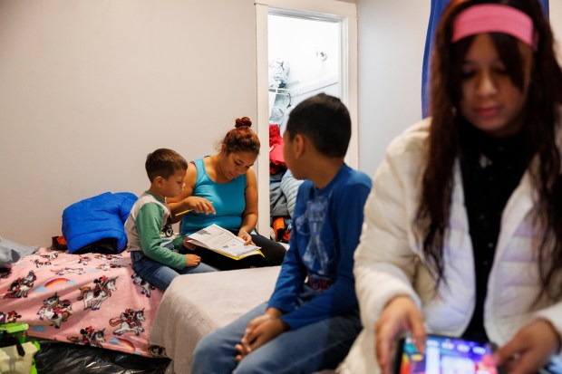 Rauly Otero, 6, from left, his mother Dalia Rodríguez, 29, her son Jose Manuel Rodriguez, 10, and his sister Ronneli Otero, 15, sit in their room before leaving for school in the home they share with several migrant families on Jan. 30, 2024 in Chicago. The home is owned by property manager Chris Amatore. (Armando L. Sanchez/Chicago Tribune)