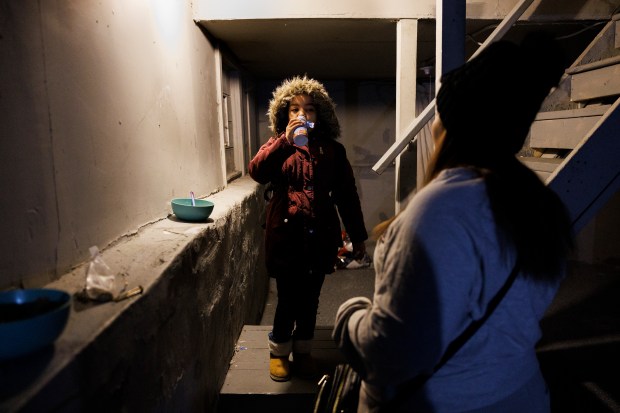 Joselin Mendoza, right, gets her daughter Ireanyerlin Hernandez, 8, ready for school in the basement where they live in the Roseland neighborhood of Chicago on Jan. 30, 2024. The home is owned by property manager Chris Amatore who is helping to house migrants across Chicago. (Armando L. Sanchez/Chicago Tribune)