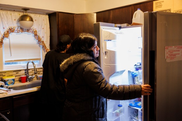 Maria Malpica, 28, of Venezuela, looks inside the refrigerator in the home she shares with other migrant families on Jan. 29, 2024, in Chicago. (Armando L. Sanchez/Chicago Tribune)