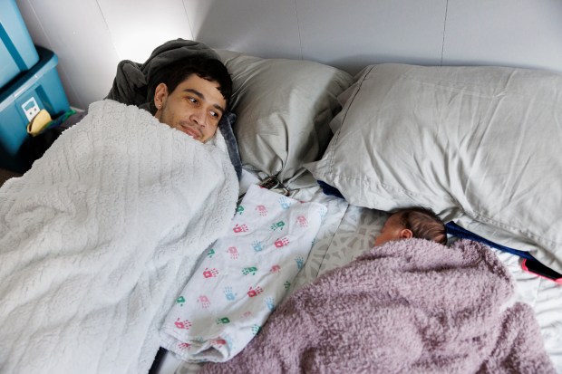 Marilieser Gil-Blanco en la cama con su hija recién nacida, Ashley, el 31de enero de 2024. Gil-Blanco perdió la capacidad de caminar debido a una rara afección de la columna en el viaje a los EE.UU. (Armando L. Sanchez/Chicago Tribune)