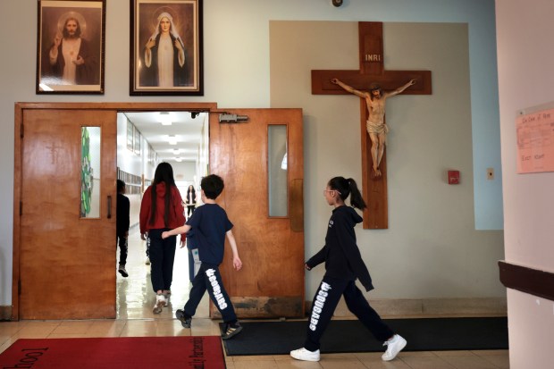 Students walk past religious images and a crucifix as they walk towards their classrooms at St. Odilo's Catholic Elementary School in Berwyn, Friday, Feb 2, 2024. St. Odilo School is one of two Catholic schools closing in Jun e citing the loss of the Invest in Kids Scholarship program. Principal asked that we avoid direct or clear shots of the student's faces. (Antonio Perez/ Chicago Tribune)