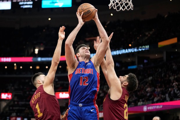 Detroit Pistons forward Danilo Gallinari (12) shoots between Cleveland Cavaliers guard Max Strus (1) and forward Georges Niang, right, in the second half of an NBA basketball game, Wednesday, Jan. 31, 2024, in Cleveland. (AP Photo/Sue Ogrocki)