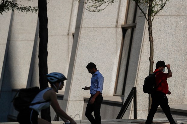 People walk and bike on South Dearborn Street outside of Chase Tower and Exelon Plaza in Chicago on July 6, 2021. (José M. Osorio/ Chicago Tribune)