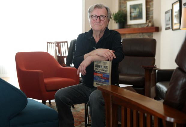 Author Mark Larson with his new book, "Working in the 21st Century," at his Chicago home on Feb. 15, 2024. (John J. Kim/Chicago Tribune)