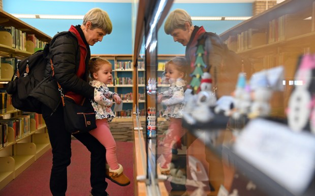 Jenna MacPhail, 2, of Arlington Heights, looks at the display case in the company of her grandmother Janet MacPhail of Steamboat Springs, Colorado, and also formerly of Northbrook, at Kids' World in the Arlington Heights Memorial Library on Feb. 1, 2024 in Arlington Heights.