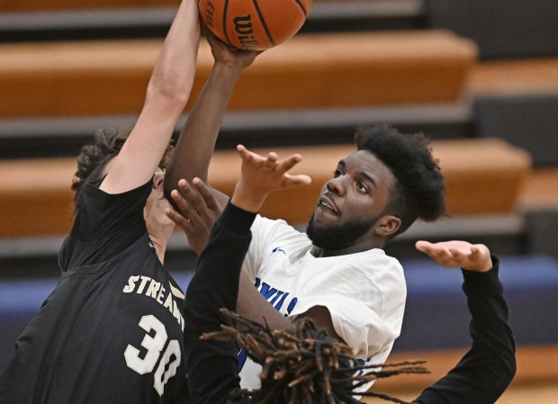 Larkin's Leandre Williams (0) has a shot rejected by Streamwood's Peyton Clements (30) during the 1st quarter of Monday's IHSA Class 4A Conant Regional Quarterfinal, February 19, 2024. Larkin won the game, 77-30. (Brian O'Mahoney for the The Courier-News)