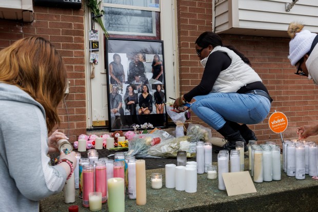 Ayanna kneels next to flowers as family, friends, and members of the community attend a vigil after seven people were killed in two shootings on the same block in Joliet on Jan. 28, 2024. (Armando L. Sanchez/Chicago Tribune)