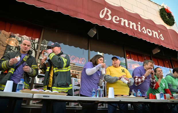 From left to right, Evanston Fire personnel Jack Conner, firefighter/paramedic, Kevin Roche, fire captain, Kelly Carlton and Pat Van, both of Wilmette, and future first place winners Frank Wach of Norwood Park and Teddy Delacruz of Wood Dale compete at the annual Paczki Eating Contest at Bennison's Bakery in Evanston on Feb. 10, 2024.