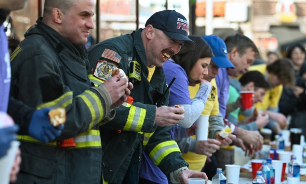 From left, Evanston Fire personnel Jack Conner, firefighter/paramedic, smiles while contest teammate Kevin Roche, fire captain, lets out a laugh during the annual Paczki Eating Contest at Bennison's Bakery in Evanston on Feb. 10, 2024.