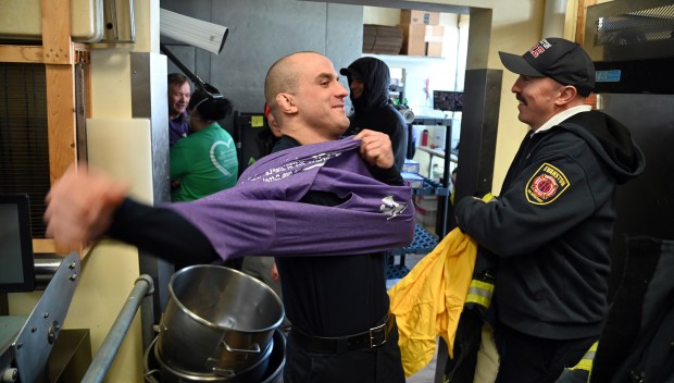 Left, Evanston Fire personnel Jack Conner, firefighter/paramedic, puts on the event t-shirt. On right is contest teammate Kevin Roche, fire captain, before the annual Paczki Eating Contest at Bennison's Bakery in Evanston on Feb. 10, 2024.