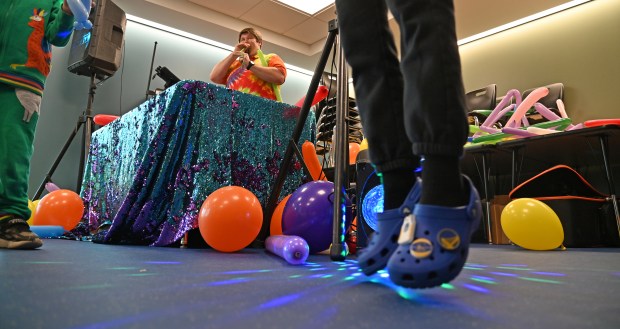 Airborne croc type sandals show youthful flight and delight. Top left, Ryan Freeman of Woodstock, balloon and performance artist, oversees the dance party during Subzero Shenanigans at the Weinberg Family Recreation Center on Feb. 19, 2024 in Glencoe. Karie Angell Luc for Pioneer Press