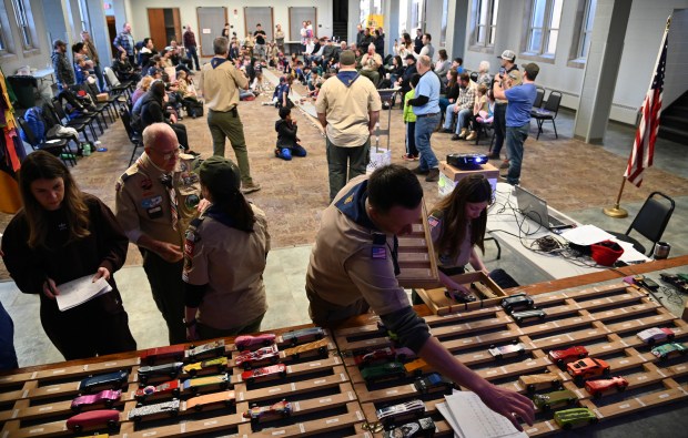 Cars roll down the track amid a room full of activity at the Pinewood Derby at Westminster Hall at the Village Church of Northbrook on Feb. 17, 2024 in Northbrook. Karie Angell Luc for Pioneer Press.