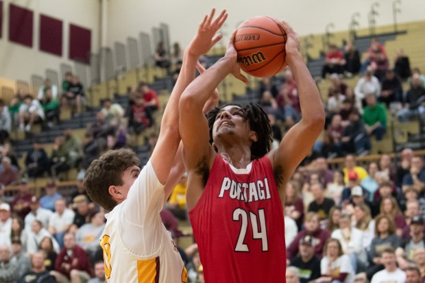 Portage forward Jaelyn Johnson puts a shot up under pressure by Chesterton forward Nathan Nix during their game in the first round of the Class 4A Chesterton Sectional on Tuesday, February 27, 2024. (Kyle Telechan/for the Post-Tribune)