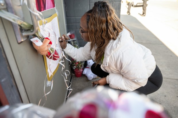 Gary resident Arkena Jackson signs a poster at a memorial in front of Fatso's Pub in honor of pub owner, her friend, Crystal Kennebrew, who was killed in a shooting in Indianapolis Monday morning, on Tuesday, February 20, 2024. (Kyle Telechan for the Post-Tribune)