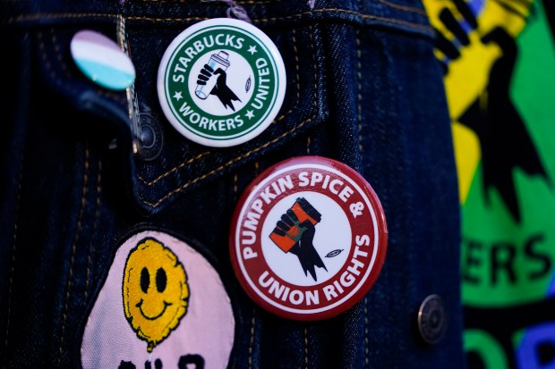 Employee Quint Palermo wears union pins on their jacket as Starbucks workers participate in a walkout and strike during the company's Red Cup Day Thursday, Nov. 16, 2023, at the company's first Reserve roastery in Seattle.