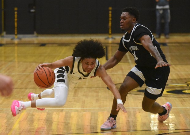 Mount Carmel's Noah Mister (2) looses his feet as he is fouled by Hyde Park's Germaine Benson (11) during the Class 3A Hinsdale South Sectional semifinals Tuesday, February 27, 2024 in Darien, IL. (Steve Johnston/Daily Southtown)