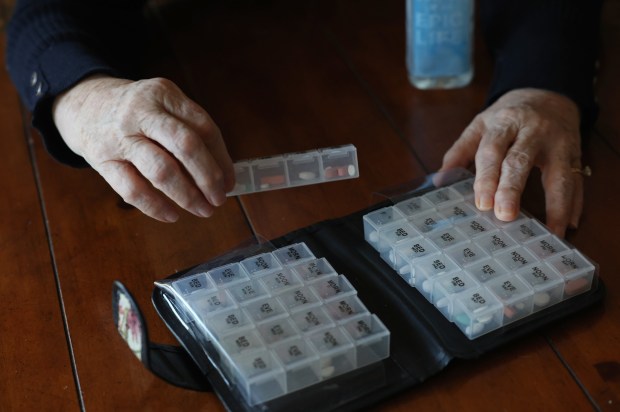 Carol McCabe shows the four-times-a-day series of medications she is required to take as a result of organ transplant surgery on Saturday, Feb. 17, 2024, in Clarendon Hills. (John J. Kim/Chicago Tribune)