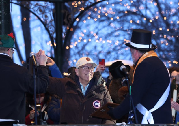 WGN weatherman Tom Skilling high-fives Rick Bellairs, left, as he introduced to the crowd in Woodstock Square at the Groundhog Day celebration on Feb. 2, 2024, in Woodstock. (Stacey Wescott/Chicago Tribune)