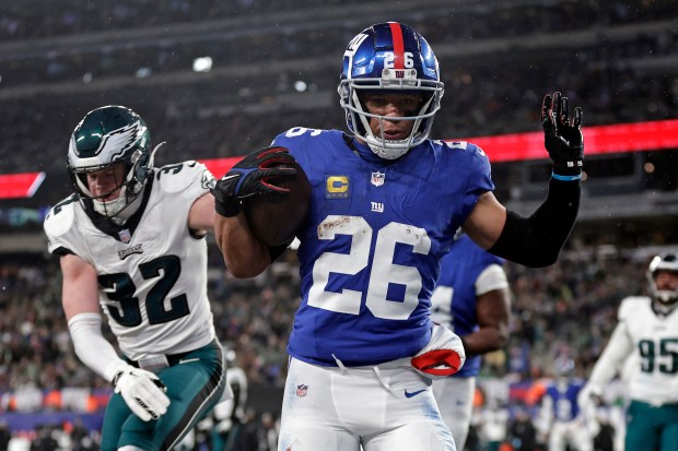 Giants running back Saquon Barkley rushes for a touchdown past Eagles safety Reed Blankenship on Jan. 7, 2024, in East Rutherford, N.J.