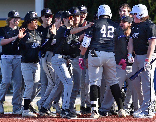 Plano's Jason Phillips (42) is mobbed by teammates after hitting a home run during a game against Aurora Central Catholic Monday, March 11, 2024, in Aurora.(Jon Cunningham/for The Beacon-News)