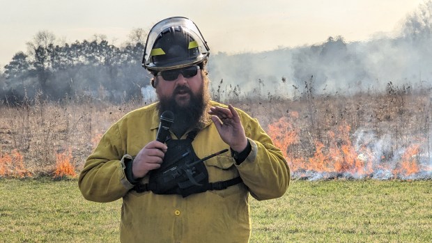 Kane County Forest Preserve District Senior Restoration Technician and frequent Burn Boss Peter Dall tells the crowd who gathered to see the controlled burn on Thursday in St. Charles that the fires are essential to the maintenance of the district's wild lands. (R. Christian Smith / The Beacon-News)