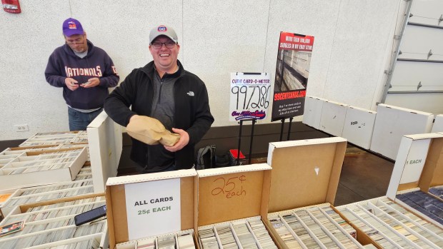 Beau Thompson, who is closing in on having one million Chicago Cubs baseball cards, reaches into a bag to pull out more cards for his booth at the Premier Card Show at the Kane County Fairgrounds in St. Charles on Saturday.