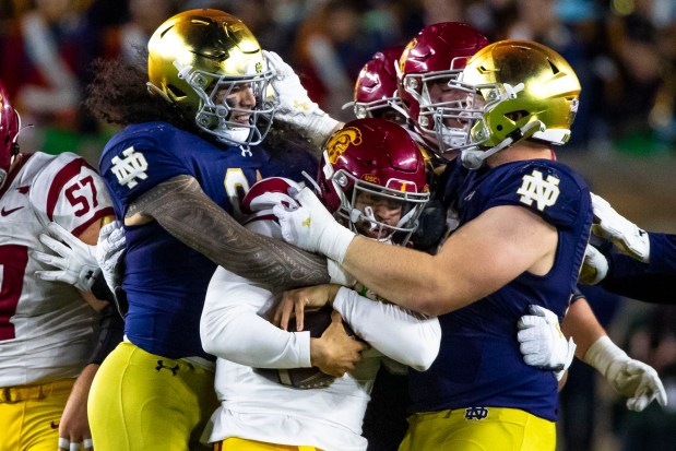 Notre Dame linebacker Marist Liufau, left, and Notre Dame defensive lineman Rylie Mills (99) wrap up Southern California quarterback Caleb Williams (13) during the second half of an NCAA college football game, Oct. 14, 2023, in South Bend, Ind. (AP Photo/Michael Caterina)