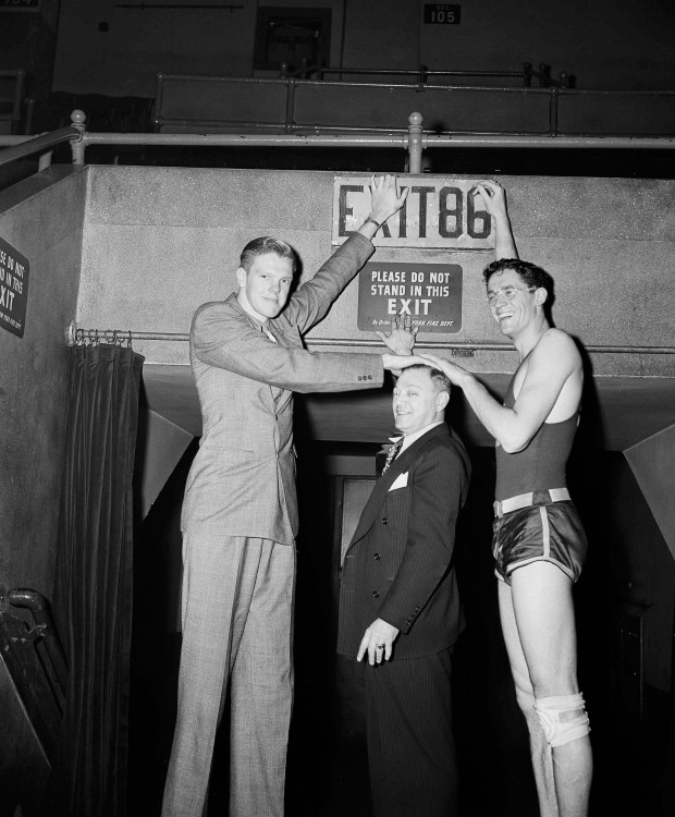 Bob Kurland, left, seven-footer from the Oklahoma Aggies basketball team and George Mikan of DePaul University, ranging 6 feet 9 inches, tower over "Cappy" Lane, five-and-a-half foot timer of events at New York's Madison Square Garden, March 28, 1945. Oklahoma and De Paul meet in the Garden March 29 for the National Collegiate Basketball Championship. (AP Photo/Anthony Camerano)SENDER: ?Powers, Ian? SUBJECT: Bob Kurland