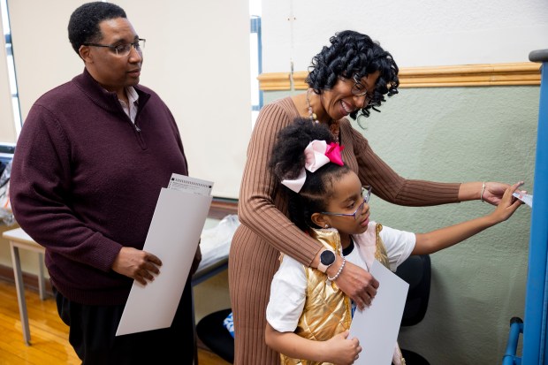 City Treasurer Melissa Conyears-Ervin, candidate for Congress in the 7th District in Illinois, turns in her ballot into an auxiliary ballot box with her daughter, Geneva, 7, during the Illinois primary election on March 19, 2024, at Marshall High School in Chicago. Conyears-Ervin's husband, Ald. Jason Ervin, 28th, waits his turn. (Vincent Alban/Chicago Tribune)