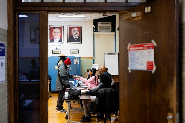 Poll worker Avaria Jones, right, hands paperwork to voter Tommie Brown during the Illinois primary election on March 19, 2024, at Marshall High School in Chicago. (Vincent Alban/Chicago Tribune)