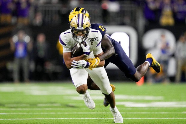 Washington wide receiver Rome Odunze is tackled by Michigan defensive back Mike Sainristil during the national championship game on Jan. 8, 2024, in Houston. (AP Photo/Eric Gay)