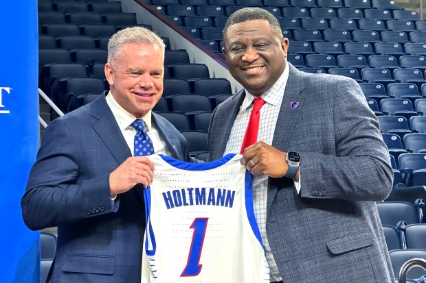 DePaul coach Chris Holtmann, left, and athletic director Dewayne Peevy hold Holtmann's jersey as they pose for photos at a news conference Monday, March 18, 2024, at Wintrust Arena. (AP Photo/Andrew Seligman)