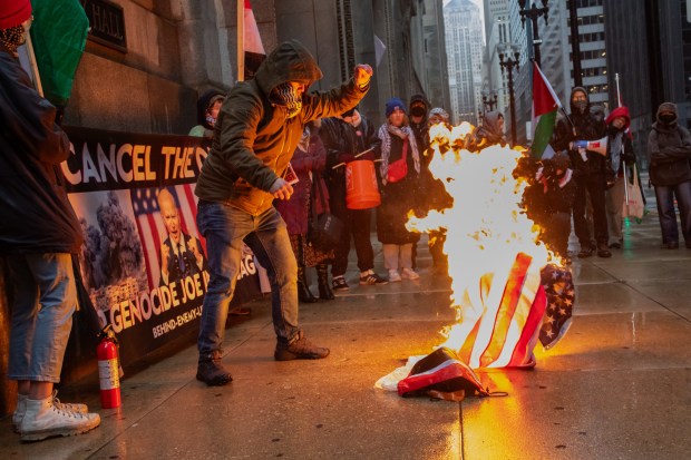 During a "Cancel the DNC" rally at City Hall, March 22, 2024, Zachary Kam, who identifies himself as a Marine Corps veteran, sets an American flag on fire. (Matthew Kaplan/ for the Chicago Tribune)