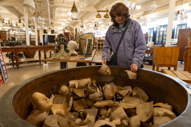A customer browses paper mache masks from the Munich Opera House on March 10, 2024, at Architectural Artifacts in River North. (Brian Cassella/Chicago Tribune)